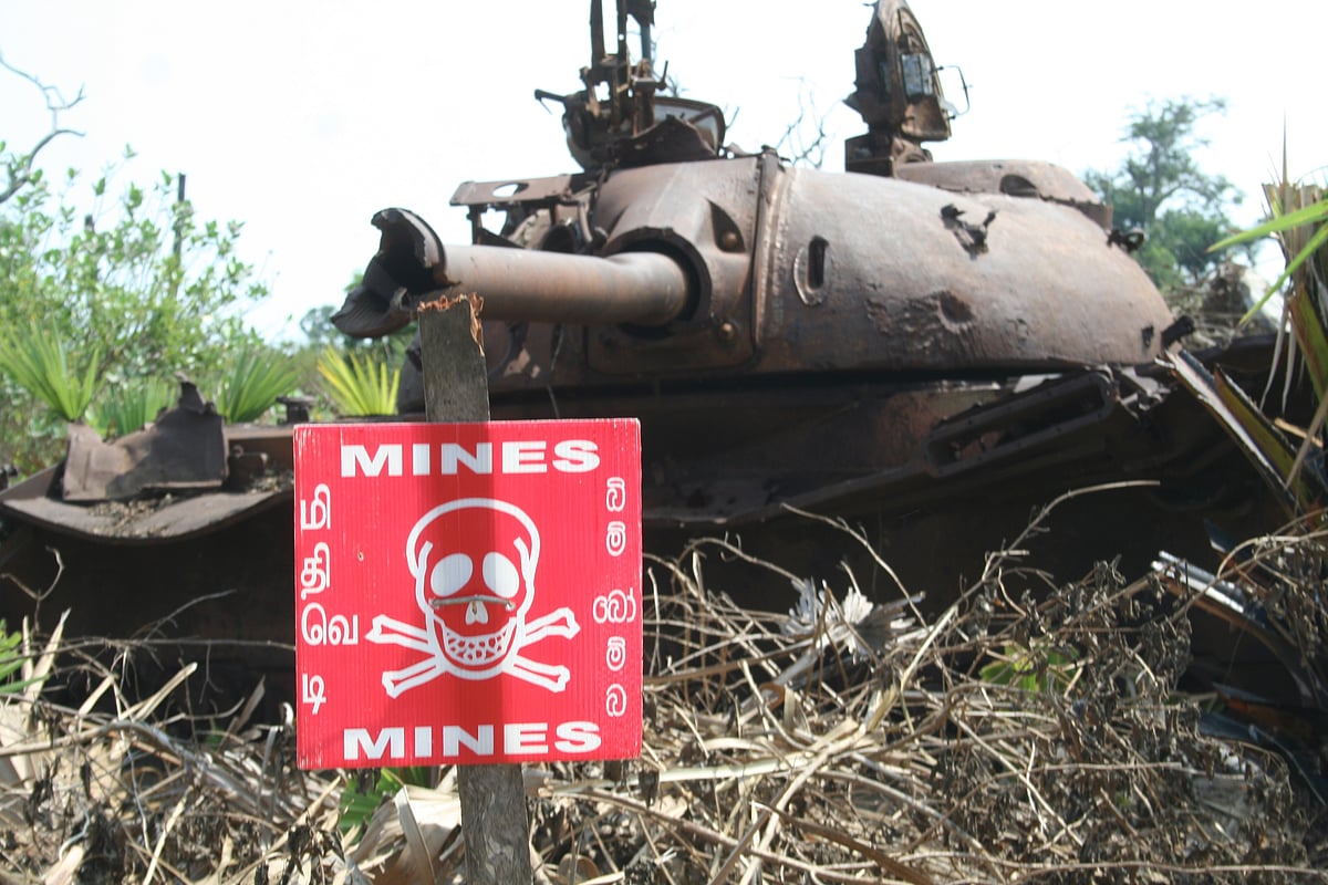 Photo of an army tank with a poster warning of mines in the foreground in Sri Lanka