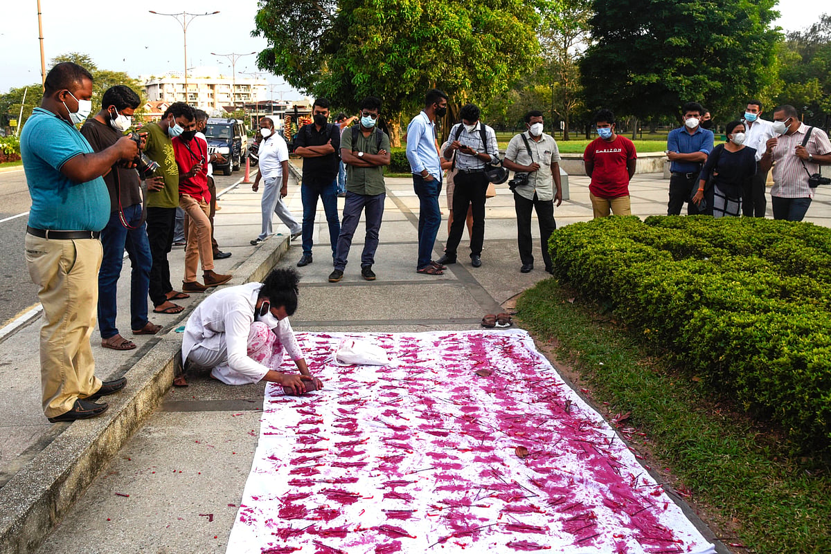 An art performance of laying down handprints in red paint on a white sheet to remember Black January which remembers journali