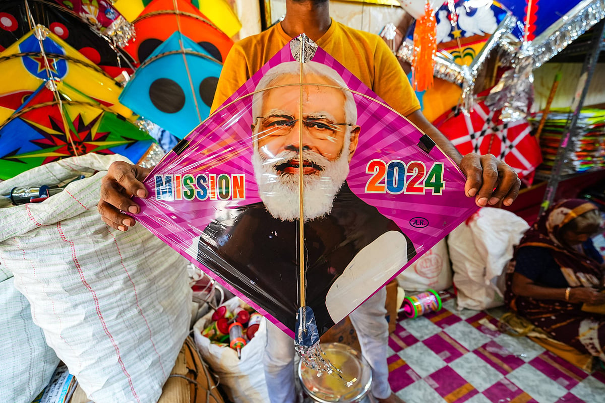 A vendor holds a colourful kite featuring a large image of the Indian prime minister Narendra Modi, with the words "MISSION 2