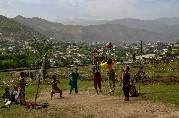 Photo of boys playing with a ball, with mountains in the backdrop