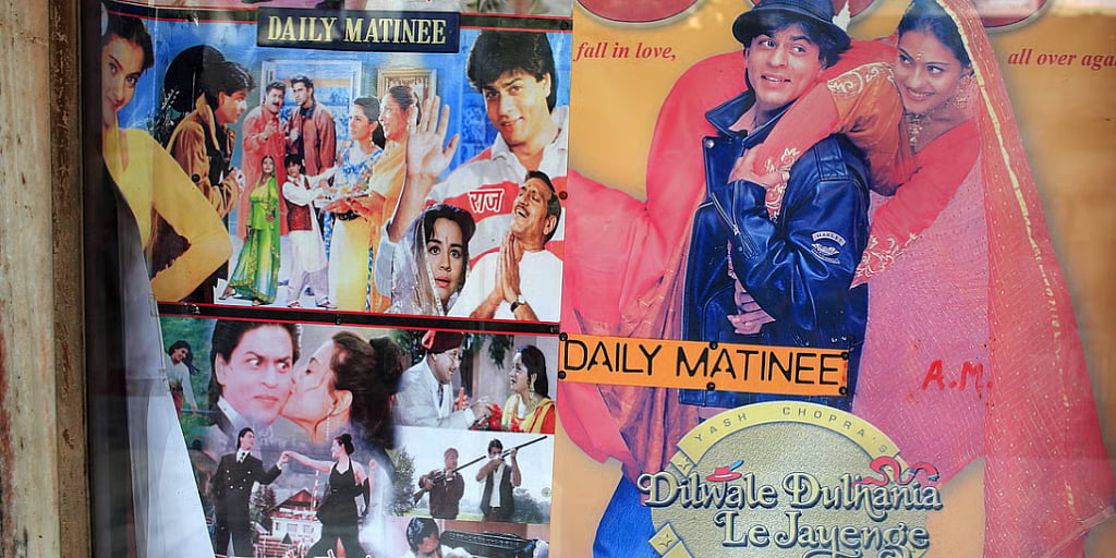 Matinee poster of the Hindi film Dilwale Dulhania Le Jayenge in Mumbai. On the right Shah Rukh Khan is wearing a leather jacket and fedora, and Kajol is in a pink embroidered shalwar. On the left are various stills of both actors in the film