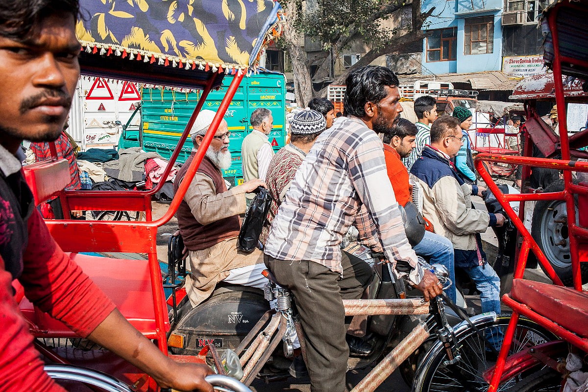 People in rickshaws and bikes waiting in the Delhi traffic