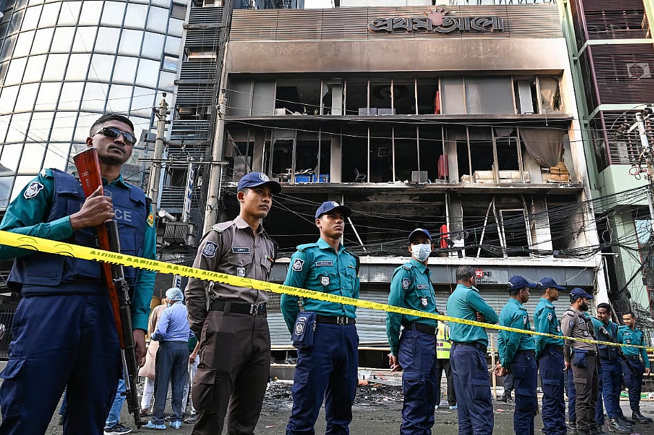 Police stand in front of the torched offices of the newspaper Prothom Alo in Dhaka, burned after the killing of student activist and politician Sharif Osman Hadi