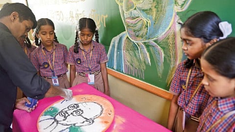 தண்ணீரில் கோலமாவைக் கொண்டு காந்தியின் உருவத்தை வரைந்த ஆசிரியர் என்.மூர்த்தி | படம்: ஜெ.மனோகரன்