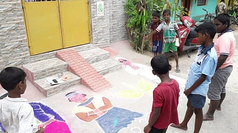 எம்ஜிஆர் உருவம் பதித்த கோலத்தை ஆர்வத்துடன் பார்க்கும் சிறுவர்கள்.