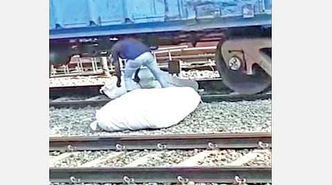 திருப்பூர் ரயில் நிலையத்தில் நின்றுகொண்டிருக்கும் ரயிலின் கீழ் புகுந்து, ஆபத்தை உணராமல் சரக்குகளை எடுத்து வரும் ரயில்வே பணியாளர்.