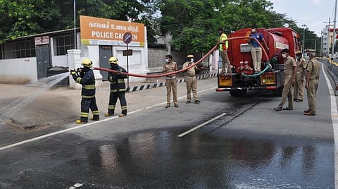 கோவை போலீஸ் எஸ்.பி. அலுவலகம் முன்பு குளோரின் தண்ணீர் தெளிப்புப் பணியில் தீயணைப்பு வீரர்கள்.