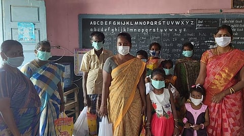 நிவாரண உதவிகள் பெற்ற பள்ளி மாணவ, மாணவிகளின் பெற்றோர்களுடன் தலைமை ஆசிரியர் அங்கயற்கண்ணி, ஆசிரியை எம்.முத்துலட்சுமி.