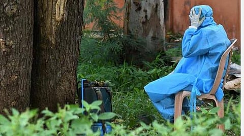 அயராத பணிகளுக்கு இடையே சற்றே ஓய்வு எடுக்கும் சுகாதாரப் பணியாளர்.