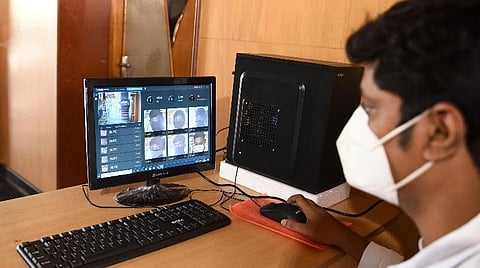 திருச்சி ஜங்ஷன் ரயில் நிலையத்துக்குள் வரும் பயணியின் வெப்பநிலையைக் கணினி திரையில் பார்வையிடும் ரயில்வே ஊழியர். | படம்: ஜி.ஞானவேல்முருகன்.