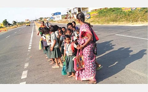 மாணவர்கள் சாலையை கடக்க உதவும் ஆசிரியர்கள்.