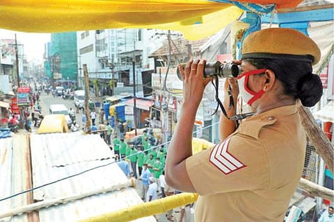 திருச்சி என்.எஸ்.பி சாலையில் தெப்பக்குளம் அருகே உள்ள கண்காணிப்பு கோபுரத்தில் இருந்து நேற்று பைனாகுலர் உதவியுடன் கண்காணிப்பு பணியில் ஈடுபட்டுள்ள பெண் காவலர்.படம்: ஜி.ஞானவேல்முருகன்