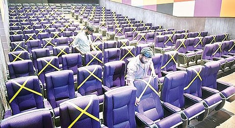 வேலூர் விருதம்பட்டு பகுதியில் உள்ள விஷ்ணு திரையரங்கில் சமுக இடைவெளி யுடன்  அமர்ந்து திரைப்படம் பார்க்கும் விதமாக இருக்கைகளை அடையாளப்படுத்தும் பணியில் ஈடுபட்டுள்ள ஊழியர்கள்.படம்:வி.எம்.மணிநாதன்.