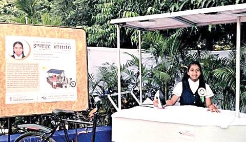 சூரிய ஒளியில் இயங்கும் இஸ்திரி வண்டியுடன் மாணவி வினிஷா.