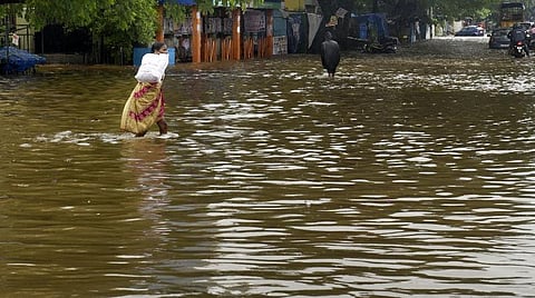 புதுச்சேரி இந்திரா காந்தி சிலை ரவுண்டானா அருகே வெள்ள நீர் சூழ்ந்து நான்கு பகுதி சாலைகளிலும் ஓடுவதால் அதில் மிதந்து செல்லும் வாகனங்கள், கடக்கும் பொதுமக்கள். படம்: எம்.சாம்ராஜ்