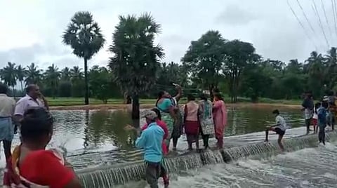 குடியாத்தம் அடுத்த எர்த்தாங்கல் ஏரியில் இருந்து வெளியேறி வரும் தண்ணீரை வேடிக்கை பார்க்க திரண்ட அப்பகுதி மக்கள்.