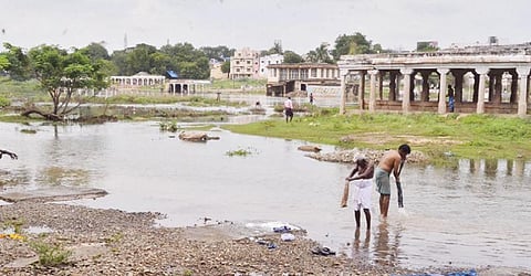 திருநெல்வேலி கொக்கிரகுளத்தில் தாமிரபரணியின் கரையையொட்டி  வெள்ளம் ஓடுவதால், கரையோரத்திலேயே பொதுமக்கள் குளிக்கின்றனர். படம்: மு.லெட்சுமி அருண்.