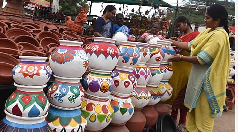 கோவை மேட்டுப்பாளையம் சாலை, கவுண்டம்பாளையம் அருகே விற்பனைக்கு வைக்கப்பட்டுள்ள மண்பானைகளை வாங்கும் வாடிக்கையாளர்கள். | படம்: ஜெ.மனோகரன்.