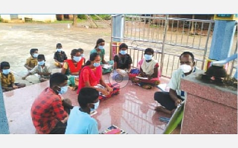 காளையார்கோவில் அருகே அரியநாச்சி குடியிருப்பில் உள்ள கோயிலில் மாணவர்களுக்கு பாடம் கற்பிக்கும் ஆசிரியர்.