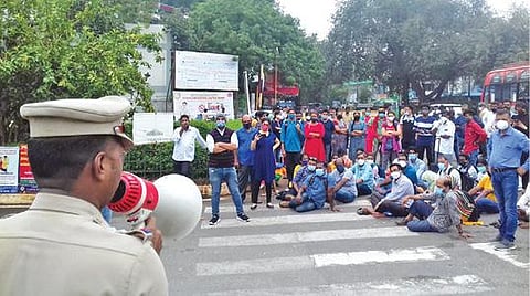 ஜிப்மர் நுழைவாயில் முன்பு போராட்டத்தில் ஈடுபட்டவர்களை ஒலிப்பெருக்கி மூலம் கலைந்துபோக சொல்லும் போலீஸார்.