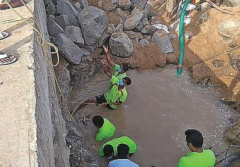 விழுப்புரம் அருகே தடுப்பணையில் சிக்கிய  இளைஞர் உடலை மீட்க  பள்ளம் தோண்டப்பட்டது. கயிறு கட்டி உடலை  மீட்கும்  பணியில் ஈடுபட்ட தீயணைப்பு வீரர்கள்.உள்படம்: விநோத்குமார்.