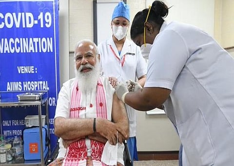 கேரளா- புதுச்சேரி செவிலியர்; அசாம் துண்டு, மேற்குவங்க மாநில உடை: பிரதமர் மோடி தடுப்பூசியிலும் தேர்தல் பிரச்சாரம்?