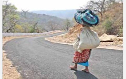 கிருஷ்ணகிரி அடுத்த ஏக்கல்நத்தம் கிராமத்துக்கு மலைப்பாதையில் புதிதாக அமைக்கப்பட்டுள்ள தார் சாலை வழியே நடந்து செல்லும் மூதாட்டி. படம்: எஸ்.கே.ரமேஷ்