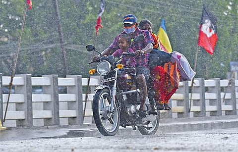 சேலம் மாவட்டம் எடப்பாடி பேருந்து நிலையம் அருகே நேற்று மாலை பெய்த மழையில்  நனைந்தவாறு குடும்பத்துடன் சென்ற வாகன ஓட்டி. 	படம்: எஸ். குரு பிரசாத்.