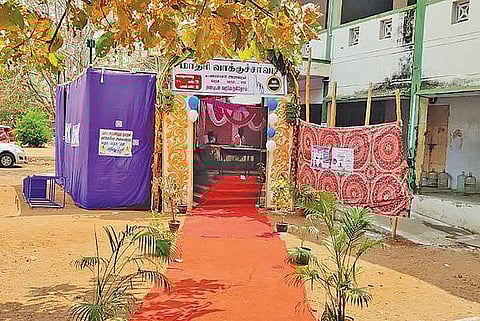 உளுந்தூர்பேட்டை அரசு ஆண்கள் மேல்நிலைப்பள்ளியில் உள்ள வாக்குச் சாவடியில் வாக்காளர் ஒருவருக்கு வழங்க பூத் ஸ்லிப்பை தேடும் பணியாளர்.