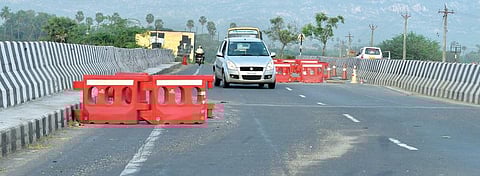 தூத்துக்குடி மாவட்டம் வல்லநாடு தாமிரபரணி ஆற்றுப்பாலத்தில் புதிதாக சேதமடைந்த பகுதி சாலை தடுப்புகள் கொண்டு மறைக்கப்பட்டுள்ளதால், சிரமப்பட்டு அந்த பகுதியை கடக்கும் வாகனங்கள். 			               படம்: என்.ராஜேஷ்