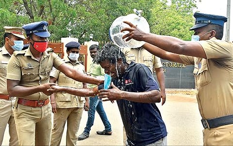 தூத்துக்குடி ஆட்சியர் அலுவலகம் முன்பு உடலில் பெட்ரோல் ஊற்றி தீக்குளிக்க முயன்ற ஆனந்தன் மீது போலீஸார் தண்ணீரை ஊற்றி தடுத்து நிறுத்தினர். 							    படம்: என்.ராஜேஷ்