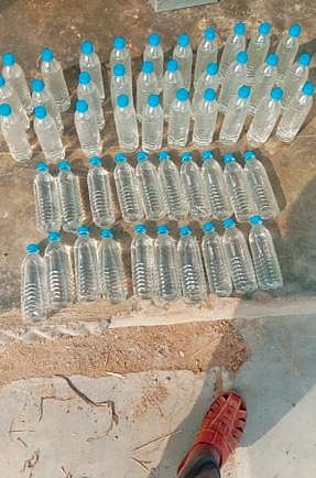 புதூர் கிராமத்தில் தண்ணீர் பாட்டிலில் அடைத்து விற்கப்படும் சாராயம்.