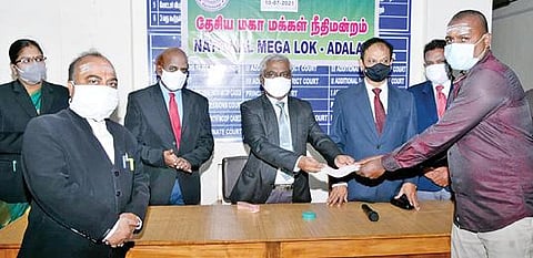 திருச்சி நீதிமன்ற வளாகத்தில் நேற்று நடைபெற்ற தேசிய மக்கள் நீதிமன்றத்தில் தீர்வு காணப்பட்ட ஒரு வழக்குதாரருக்கான காசோலையை வழங்குகிறார் மாவட்ட முதன்மை நீதிபதி கிளாஸ்டன் பிளசட் தாகூர்.