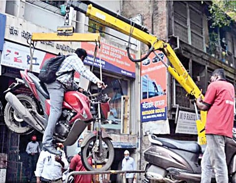 மோட்டார் சைக்கிளில் வாகன ஓட்டி அமர்ந்திருந்த நிலையில் லிப்ட் மூலம் தூக்கப்பட்ட வாகனம்.