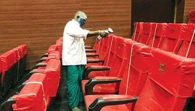 திருவண்ணாமலையில் உள்ள திரையரங்கில் இருக்கை களை கிருமி நாசினி கொண்டு சுத்தம் செய்யும் ஊழியர்.