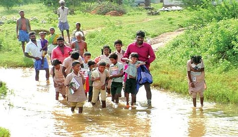 மணப்பாறை அருகே சங்கமரெட்டிபட்டியில் ஆற்று நீரில் நடந்து செல்லும் பள்ளி மாணவ, மாணவிகள்.