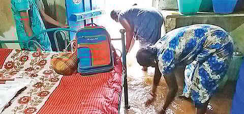 அரண்மனைப்புதூரில் வீடுகளுக்குள் புகுந்த மழை நீரை வெளியேற்றும் பெண்கள்.