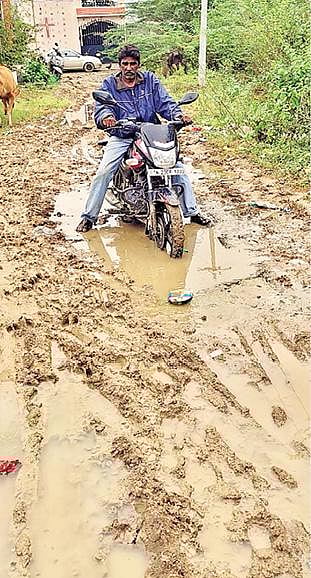 வேலூர் விருதம்பட்டு  ராஜீவ்காந்தி நகரில் சேறும், சகதியுமான சாலையில் சிக்கிய வாகன ஓட்டி.