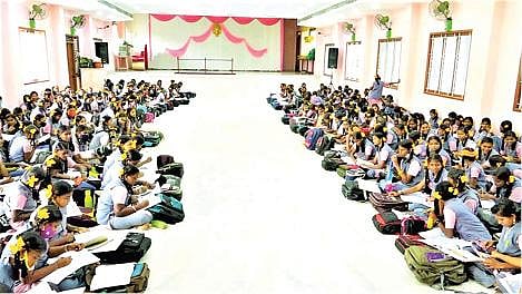 தனியார் மண்டபத்துக்கு வகுப்புகளை  மாற்றியதால் 6 முதல் 9-ம் வகுப்பு வரையிலான  மாணவிகள் ஒரே இடத்தில் அமர்ந்து பாடம் படிக்கின்றனர்.