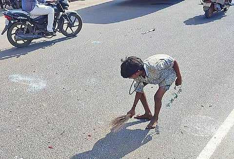 சிவகங்கை பேருந்து நிலையம் அருகே சாலையில் சிதறி கிடந்த கண்ணாடி துண்டுகளை துடைப்பத்தால் பெருக்கி அகற்றிய சிறுவன்.