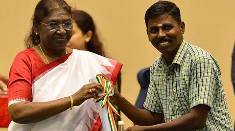 ஆசிரியர் தினத்தையொட்டி டெல்லி விக்ஞான் பவனில் நேற்று நடைபெற்ற நிகழ்ச்சியில் தேசிய நல்லாசிரியர் விருதை, தமிழகத்தின் ராமநாதபுரத்தைச் சேர்ந்த ஆசிரியர் ராமச்சந்திரனுக்கு வழங்குகிறார் குடியரசுத் தலைவர் திரவுபதி முர்மு. படம்: பிடிஐ