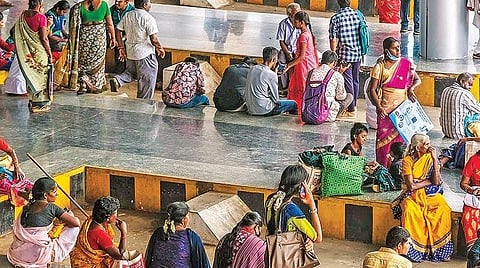 பயணிகள் காத்திருப்பு அறை செயல்படாததாலும், போதிய இருக்கைகள் இல்லாததாலும் நடைமேடையிலேயே அமர்ந்து பேருந்துக்கு காத்திருக்கும் பயணிகள்.