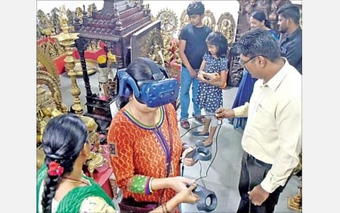 கோவை பூம்புகார் விற்பனையகத்தில் மெய்நிகர் கைவினைக் கண்காட்சி முறையில் பொருட்களை பார்வையிட்ட வாடிக்கையாளர்.  அருகில் மேலாளர் கி.ரொனல்டு செல்வஸ்டின் உள்ளிட்டோர்.  படம்: ஜெ.மனோகரன்