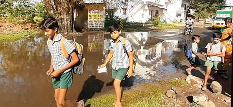 பி.துரிஞ்சிப்பட்டியில் சாலையில தேங்கி நிற்கும் கழிவு நீரை மிதித்தபடி செல்லும் பள்ளி மாணவர்கள்.