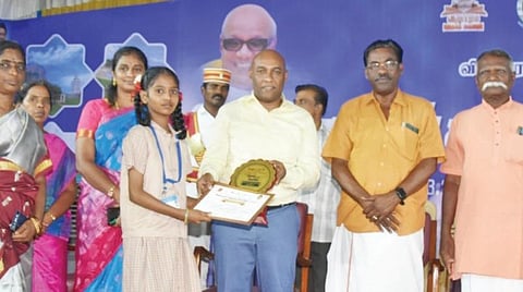 புத்தகத் திருவிழாவையொட்டி நடத்தப்பட்ட போட்டிகளில் வெற்றி பெற்ற மாணவி ஒருவருக்கு பரிசு வழங்கும் ஆட்சியர் பழனி.