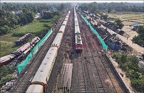 ஒடிசாவில் ரயில் விபத்து நடந்த இடத்தில் மின்வழித் தடம், தண்டவாளங்கள் சீரமைக்கப்பட்டு, நேற்று ரயில் போக்குவரத்து தொடங்கியது. விபத்தில் உருக்குலைந்த பெட்டிகள் அருகில் கிடக்க, அப்பகுதியை கடந்து செல்லும் ரயில்கள். படம்: பிடிஐ