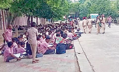 திருச்சுழியில் சாலையோரத்தில் அமர்ந்து படிக்கும் அரசு பள்ளி மாணவ, மாணவிகள்.