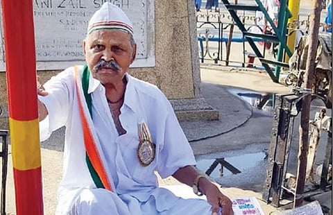 மணப்பாறையில் நேற்று காமராஜர் சிலை முன்பு கோரிக்கை அட்டைகளுடன் தர்ணாவில்  ஈடுபட்ட சுதந்திர போராட்ட தியாகி சுந்தரம்.