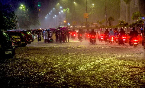 மழையின் போது சாலையில் தேங்கியுள்ள நீருக்கு மத்தியில் செல்லும் வாகனங்கள்