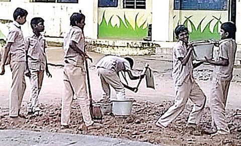 துரிஞ்சாபுரம் ஊராட்சி ஒன்றிய நடுநிலை பள்ளியில் மண் அள்ளும் பணியில் ஈடுபடுத்தப்பட்ட மாணவர்கள், வாளியில் நிரப்பப்பட்ட மண்ணை தூக்க முடியாமல் திணறினர்.